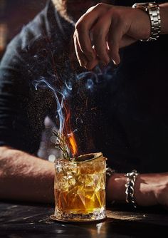 a man is pouring something into a glass filled with ice and water while sitting at a bar