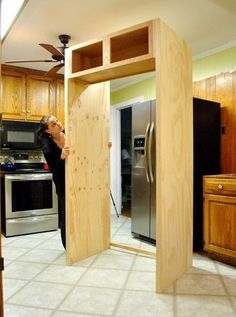 a person standing in a kitchen looking through an open door