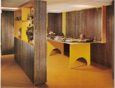 an empty room with yellow walls and wood paneling on the wall, as well as shelves filled with various items