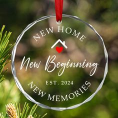 a new home ornament hanging from a pine tree with the words new beginnings on it