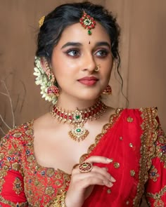 a woman in a red sari with jewelry on her neck and hands behind her head