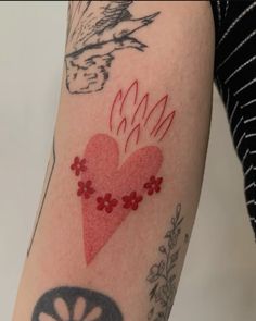 a woman's arm with tattoos on it and a red heart in the middle