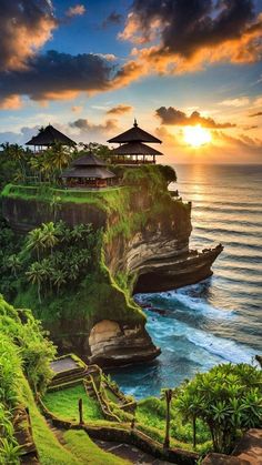 the sunset is shining over an ocean cliff with some huts on it and trees in the foreground