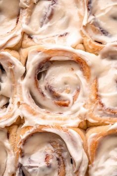 cinnamon rolls with icing sitting on top of each other in a baking pan,