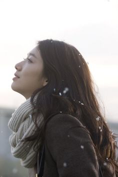 a woman standing in the snow looking up at something