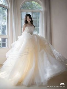 a woman in a wedding dress standing by a window