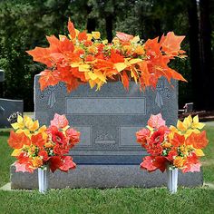 an orange and yellow wreath on top of a gravestone with flowers in the middle