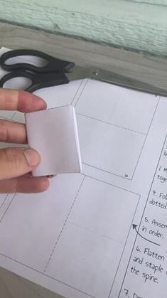 a hand holding a piece of paper next to scissors