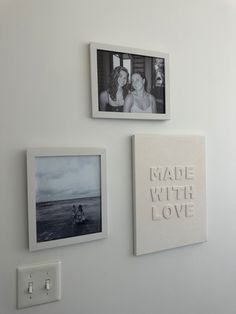 three framed photos hang on the wall next to an electrical outlet with two people kissing