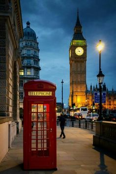 a red phone booth sitting next to a tall clock tower