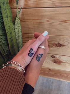 a woman's hand with a butterfly tattoo on her left wrist, next to a succulent plant