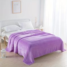 a bed with a purple comforter and pillows