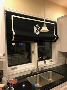 a black and white roman blind in a kitchen window with the word monogram on it