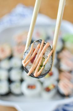 sushi being held by chopsticks with sauce on them