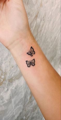 a woman's arm with two small butterflies on the left side of her wrist