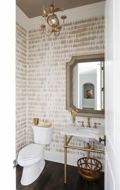 a white toilet sitting next to a sink in a bathroom under a golden chandelier