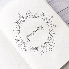 an open notebook with the word january written on it and a wreath made out of leaves