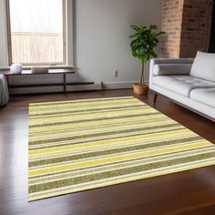 a living room with white couches and a yellow striped rug on the wooden floor