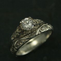 a white gold ring with a diamond in the center and filigrees around it