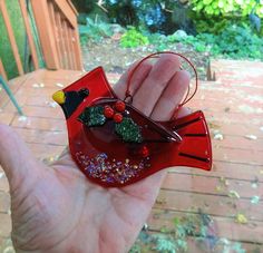 a hand holding a red glass bird ornament