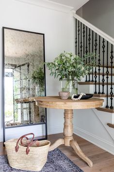 a wooden table sitting in the middle of a living room next to a stair case