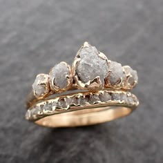 two gold wedding rings with rough white diamonds on each one, set against a black background