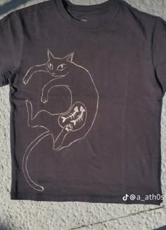 a t - shirt with a drawing of a cat sitting on it's back