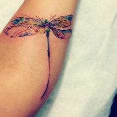 a small dragonfly tattoo on the arm