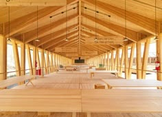 the inside of a wooden building with tables and benches on each side that are suspended from rafters