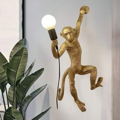 a gold monkey statue holding a light bulb and standing on its hind legs in the air