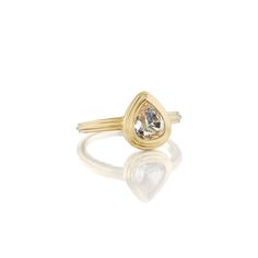 a yellow gold ring with a pear shaped diamond in the center, on a white background