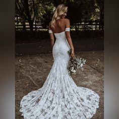 a woman in a white wedding dress is standing outside with her back to the camera