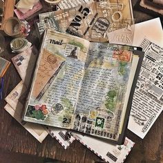 an open book sitting on top of a wooden table covered in papers and other items