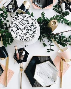 a table topped with black and white plates covered in confetti, greenery and candles