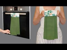 a woman is holding up a green towel in front of an oven with the door open