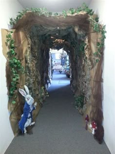 a hallway decorated with fake rocks and plants on the walls, along with stuffed animals