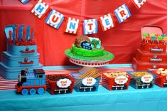 a train themed birthday party with cake and desserts on a table in front of a red backdrop