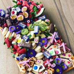 a wooden table topped with lots of different types of candies and fruit on top of it