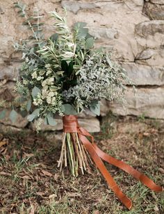 a bouquet of greenery tied to a stone wall