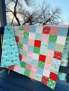 two quilts on a bench with trees in the background