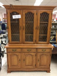 a wooden china cabinet with glass doors in a store