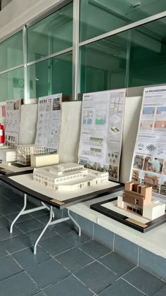 there are many model buildings on the tables in front of each other with papers attached to them