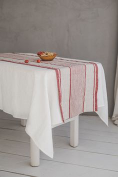 a white table with a red stripe on it and a bowl of fruit on top