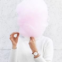 a woman holding a pink cotton candy in front of her face