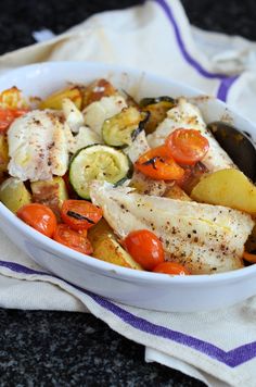 a white bowl filled with chicken and veggies on top of a blue and white towel