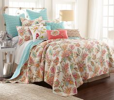 the comforter is made up with colorful pillows and bed linens on top of it