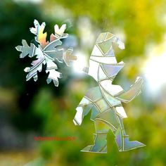 a snowflake is seen through a window with green trees in the back ground