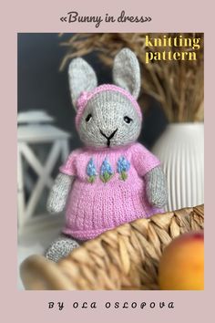 a knitted bunny in a pink dress sitting on a basket