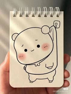 a hand holding a notebook with a drawing of a bear on it