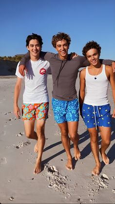 three young men are standing on the beach